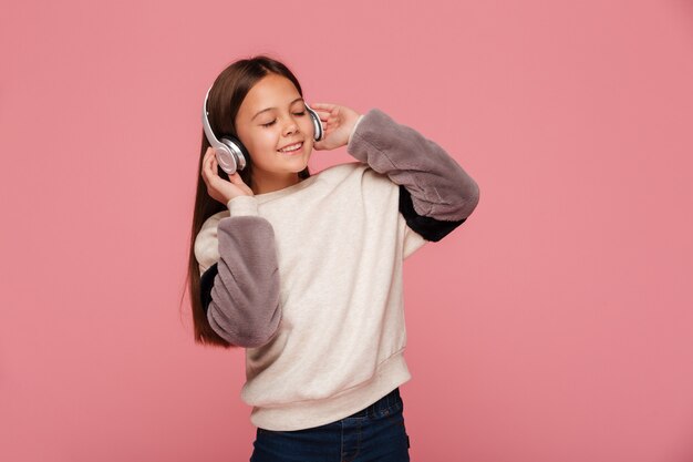 Ragazza graziosa che gode della musica in cuffie isolate