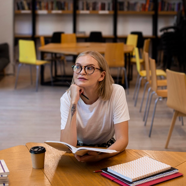 Ragazza graziosa che pensa alla biblioteca