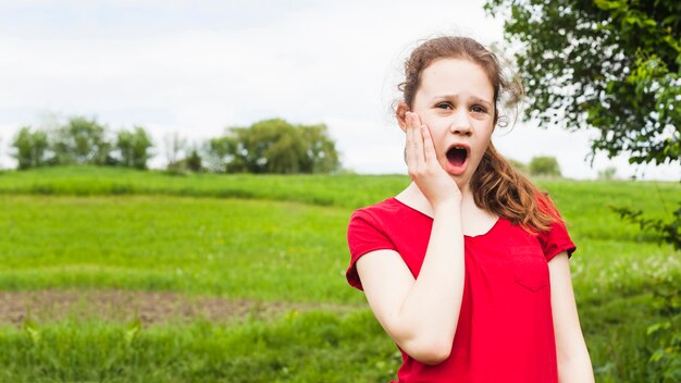 Ragazza graziosa che sta nel parco che ha mal di denti