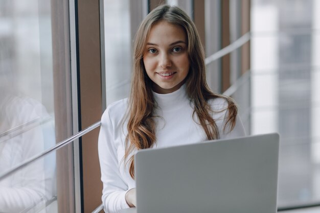 Ragazza graziosa con un computer portatile dalla finestra