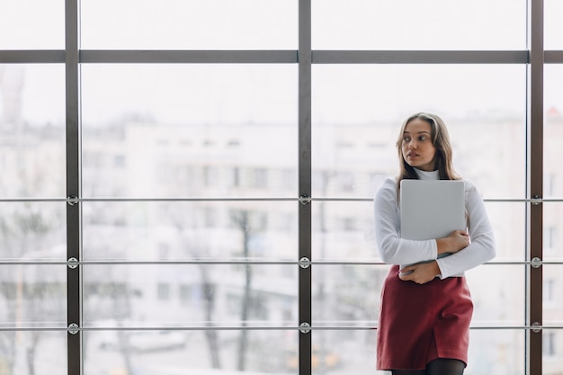 Ragazza graziosa con un computer portatile dalla finestra