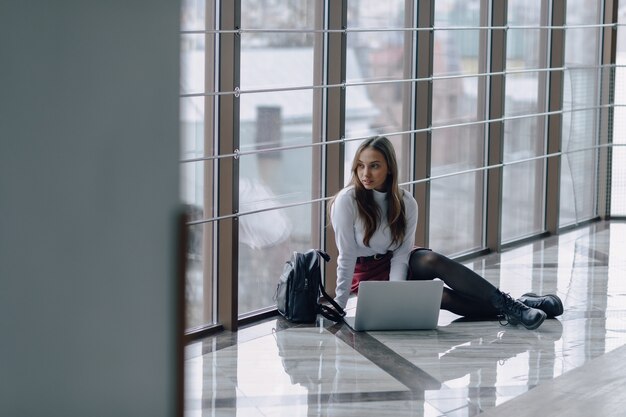 Ragazza graziosa con un computer portatile dalla finestra