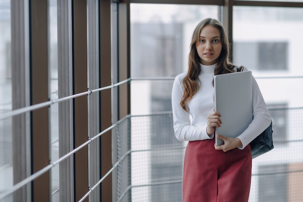 Ragazza graziosa con un computer portatile dalla finestra