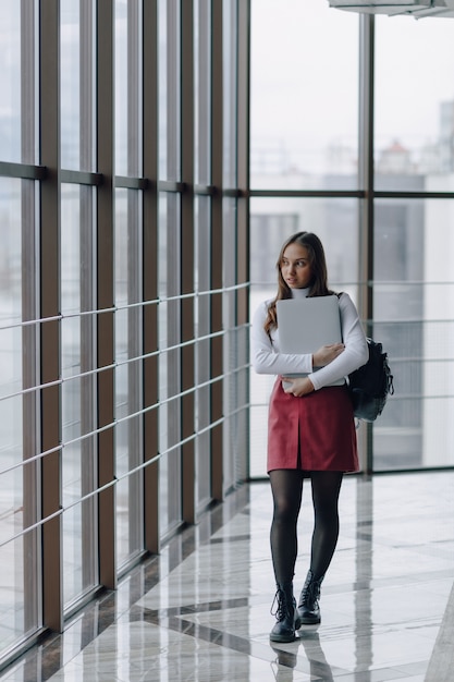 Ragazza graziosa con un computer portatile dalla finestra