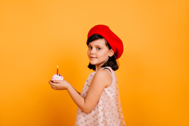 Ragazza graziosa del preteen che tiene torta con la candela. ragazzo alla moda che celebra il compleanno.