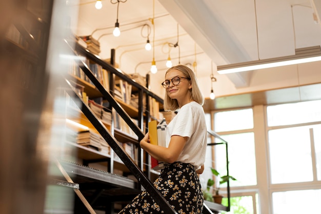 Ragazza graziosa in biblioteca