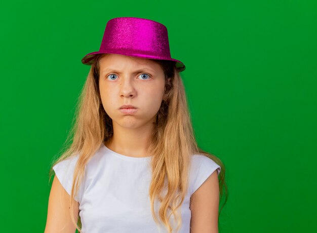 Ragazza graziosa offesa in cappello di festa con la faccia seria