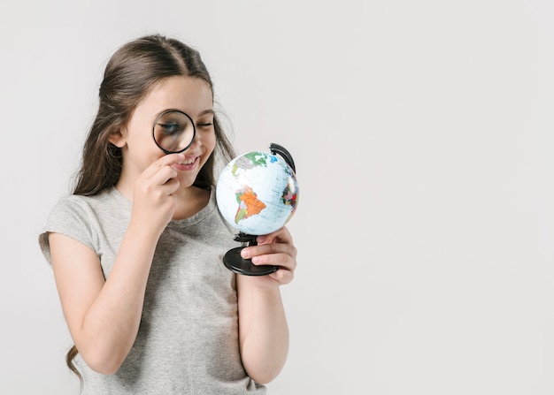 Ragazza guardando il globo con lente