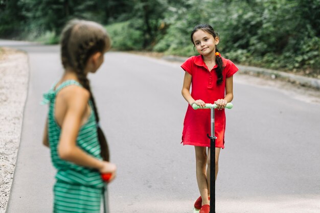 Ragazza guardando il suo amico in sella a scooter sulla strada