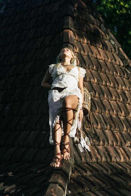 ragazza hippie con lunghi capelli biondi in un abito sul tetto.