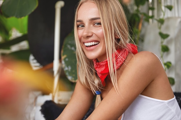 Ragazza hipster con bandana sul collo pone nella caffetteria