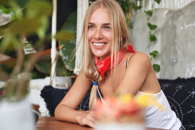 Ragazza hipster con bandana sul collo pone nella caffetteria