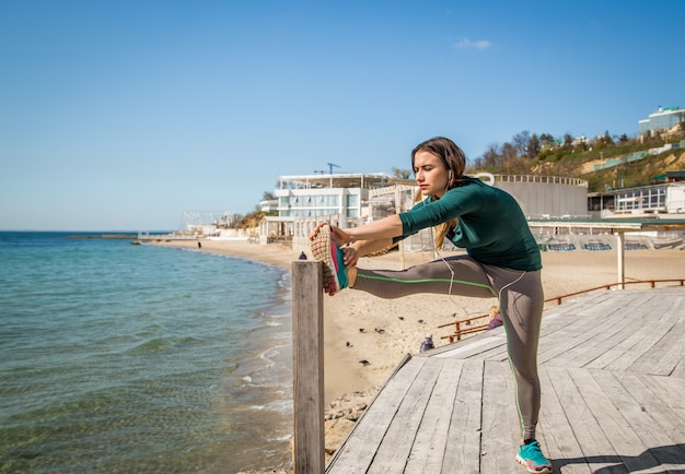 Ragazza in abiti sportivi che fa allungamento dal mare