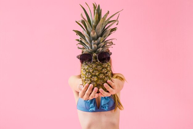 Ragazza in bikini che mostra ananas