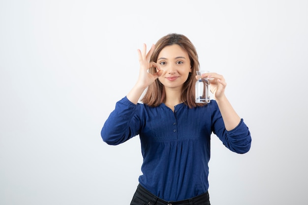 Ragazza in camicetta blu che tiene acqua e dà segno giusto.