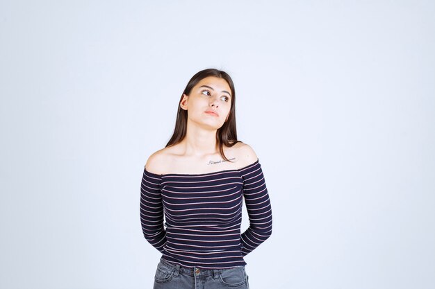 Ragazza in camicia a righe che dà pose neutre senza reazioni.