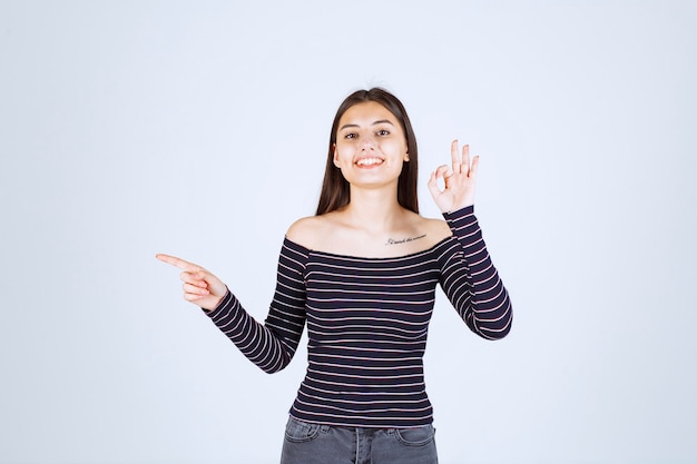 Ragazza in camicia a righe che mostra un buon segno di godimento.