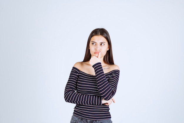 Ragazza in camicia a righe pensando e analizzando.