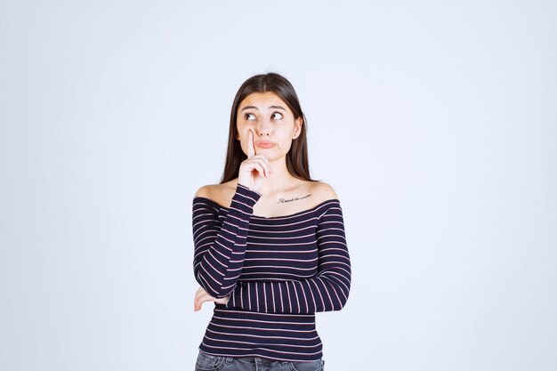 Ragazza in camicia a righe pensando e di brainstorming.