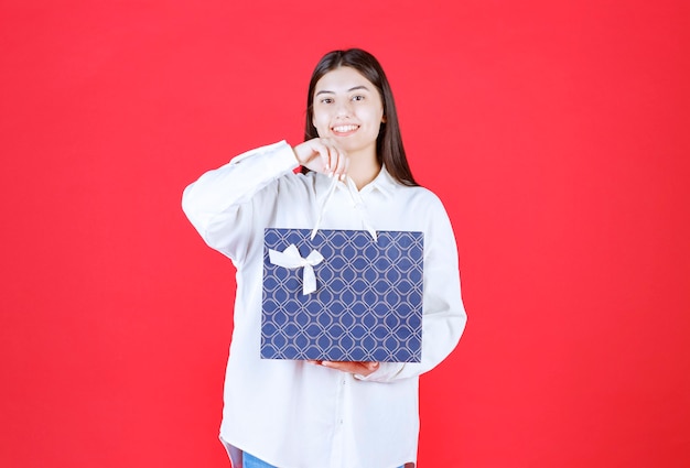 Ragazza in camicia bianca con in mano una borsa della spesa blu