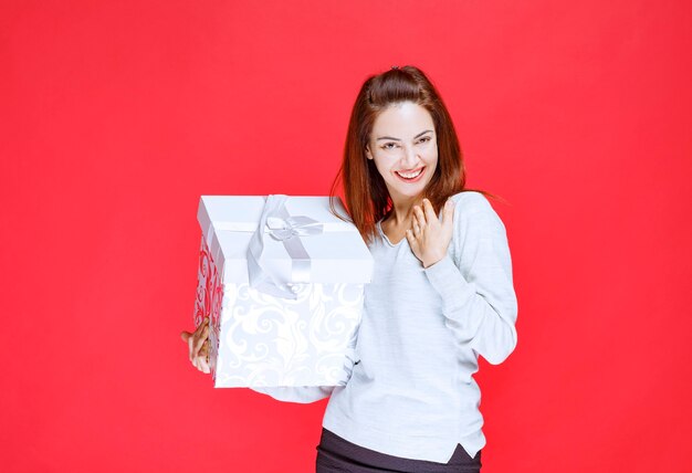 Ragazza in camicia bianca con in mano una scatola regalo stampata