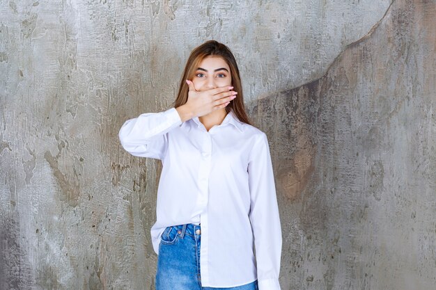 Ragazza in camicia bianca in piedi su un muro di cemento e si sente spaventata e terrorizzata