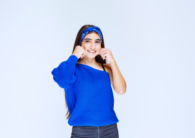 Ragazza in camicia blu che dà pose seducenti e allegre.