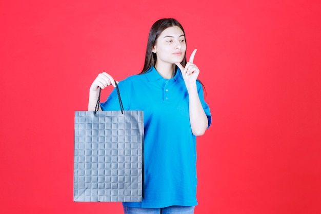 Ragazza in camicia blu con in mano una borsa della spesa viola