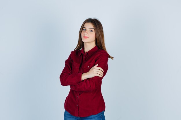 ragazza in camicia bordeaux che tiene le braccia conserte e sembra sicura.