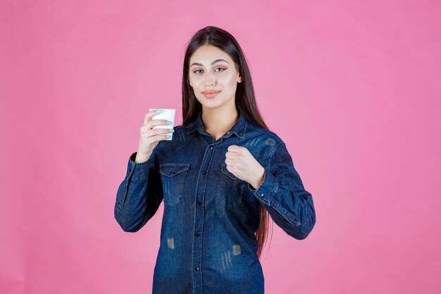 Ragazza in camicia di jeans che gode di una tazza di caffè usa e getta