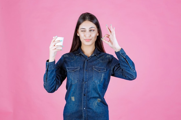 Ragazza in camicia di jeans con caffè e godersi il gusto