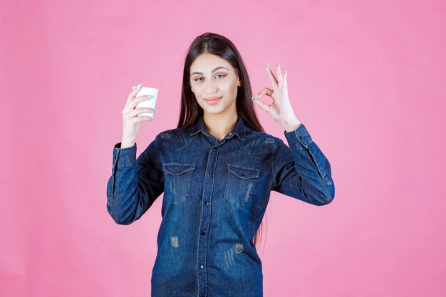 Ragazza in camicia di jeans con caffè e godersi il gusto