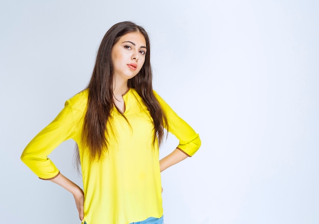 Ragazza in camicia gialla che dà pose neutre.