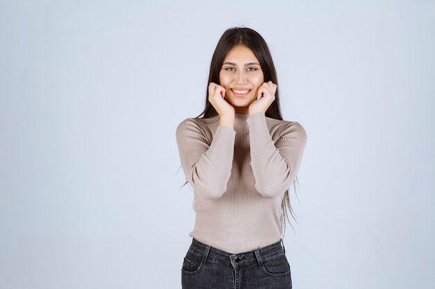 Ragazza in camicia grigia che dà pose invitanti e seducenti.