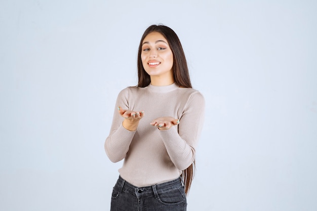 Ragazza in camicia grigia che dà pose invitanti e seducenti.