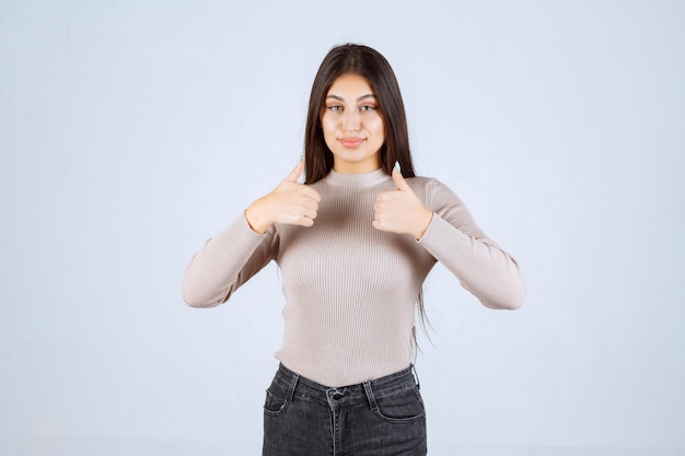 Ragazza in camicia grigia che fa il pollice sul segno.