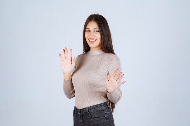 Ragazza in camicia grigia che impedisce qualcosa.