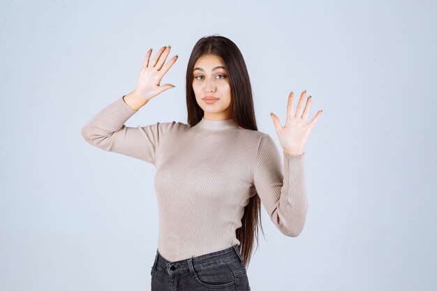 Ragazza in camicia grigia che impedisce qualcosa.