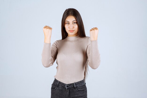 Ragazza in camicia grigia che mostra i suoi muscoli del braccio.