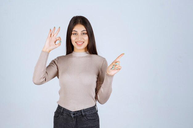 Ragazza in camicia grigia che mostra qualcosa sopra e che si eccita.