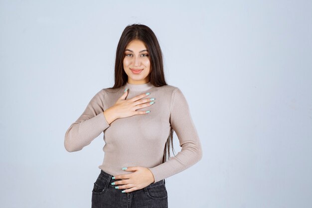 Ragazza in camicia grigia che punta a se stessa.