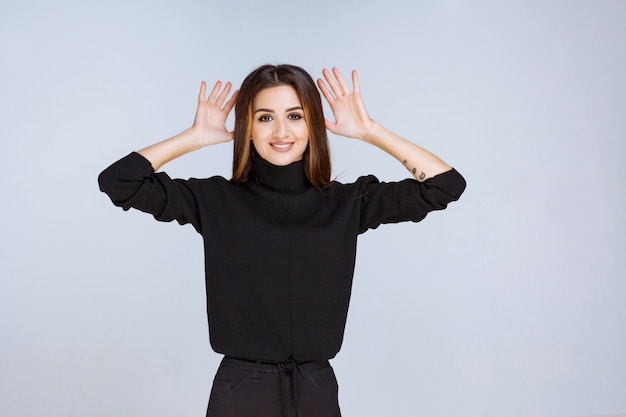 Ragazza in camicia nera che si ferma e impedisce qualcosa. Foto di alta qualità