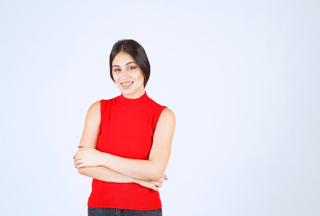 Ragazza in camicia rossa che dà pose adorabili e seducenti.