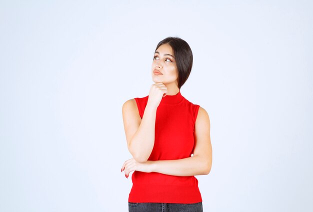 Ragazza in camicia rossa che dà pose adorabili e seducenti.