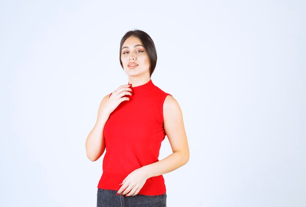 Ragazza in camicia rossa che dà pose adorabili e seducenti.