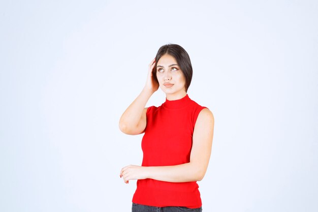 Ragazza in camicia rossa che fa il viso fastidioso e noioso.