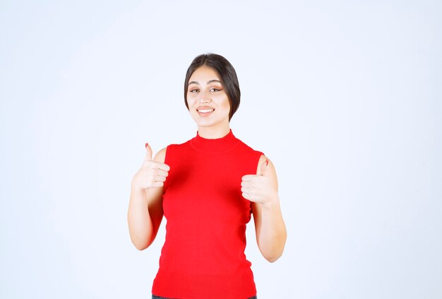 Ragazza in camicia rossa che mostra i pollici in su.