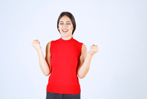 Ragazza in camicia rossa che mostra i suoi muscoli e pugni del braccio.