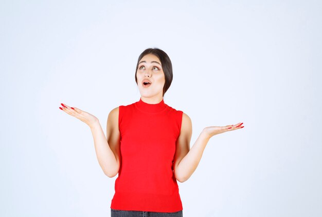 Ragazza in camicia rossa che mostra qualcosa nella sua mano aperta.