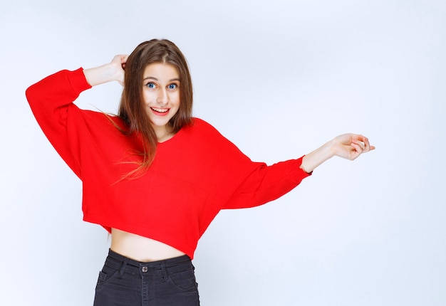 Ragazza in camicia rossa che punta a destra.